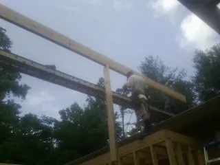 Carpenter setting a ridge beam over a new addition frame — Ice Dam Removal by Roofing Brothers in Castella