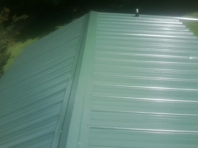 New green metal panels meeting at the ridge of a roof — Flat Roof Repair work by our crew in Castella