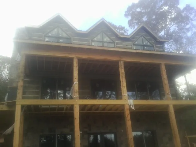 Dormers and porch framing on a large log home under construction — Roof Coating work by our crew in Castella
