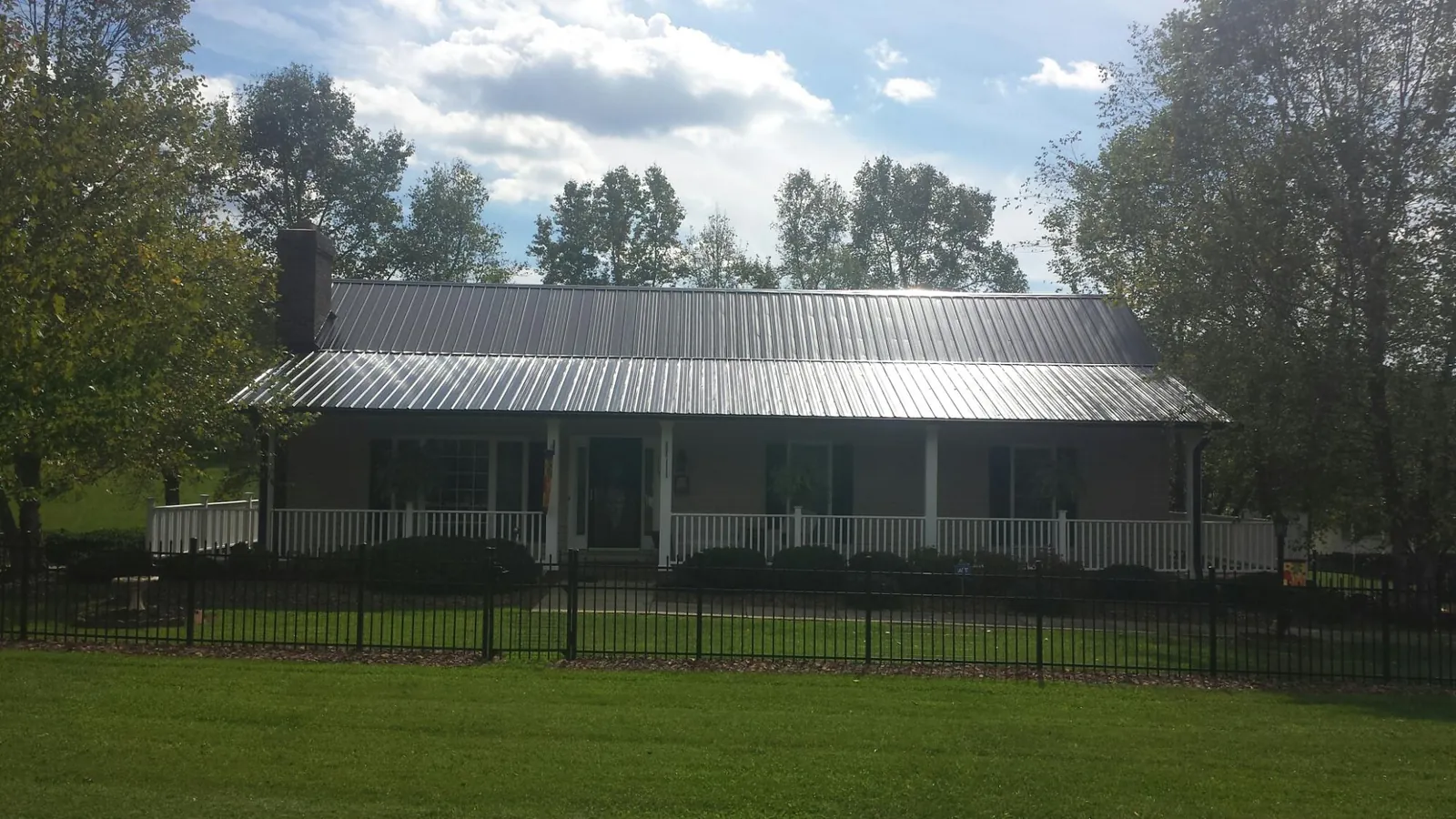 Gray metal roof on a brick ranch with a full width front porch — Gutter Guard Installation work by our crew in Castella