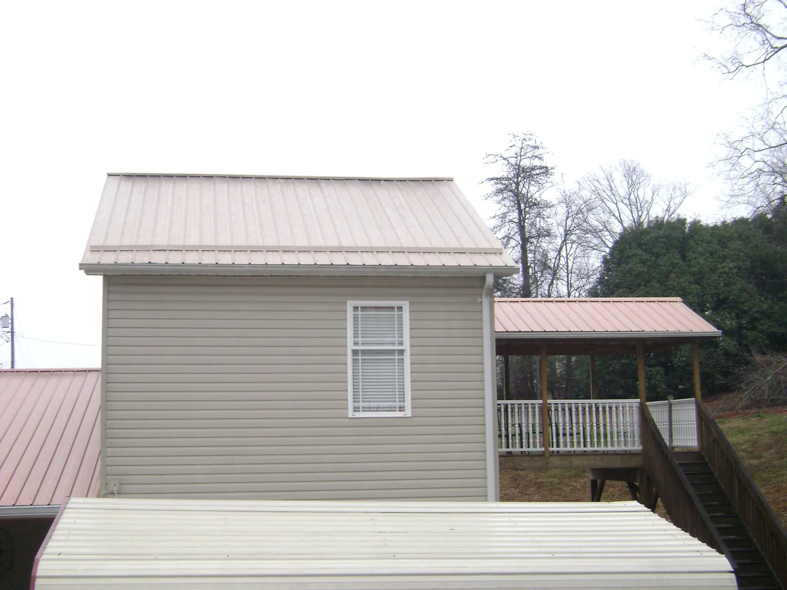 Tan metal roofs on a two story addition and attached porch, from a Roof Replacement job in Castella
