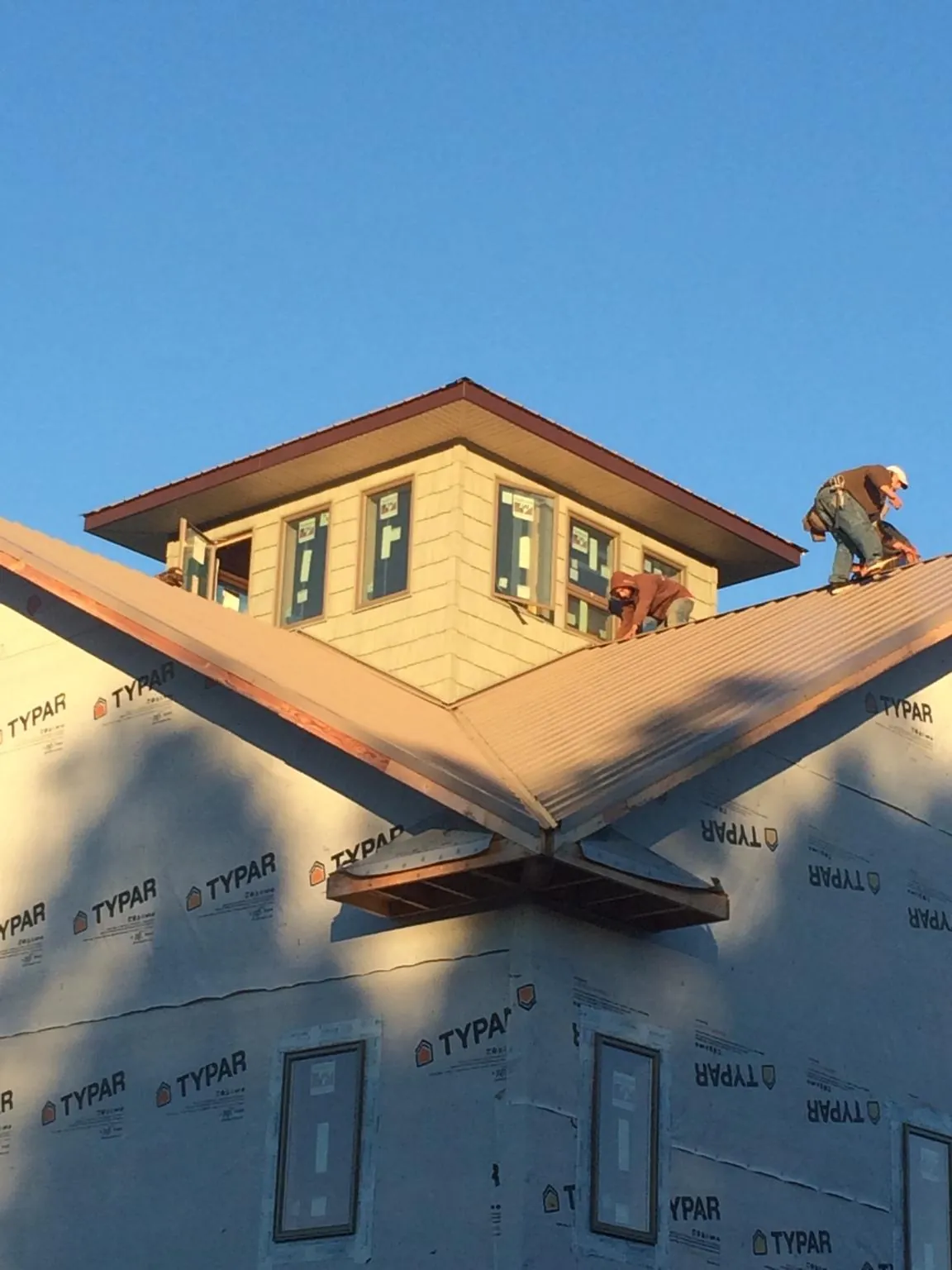 Roofers working around a rooftop cupola on a new metal roof at sunset — Roof Waterproofing in Castella by Roofing Brothers